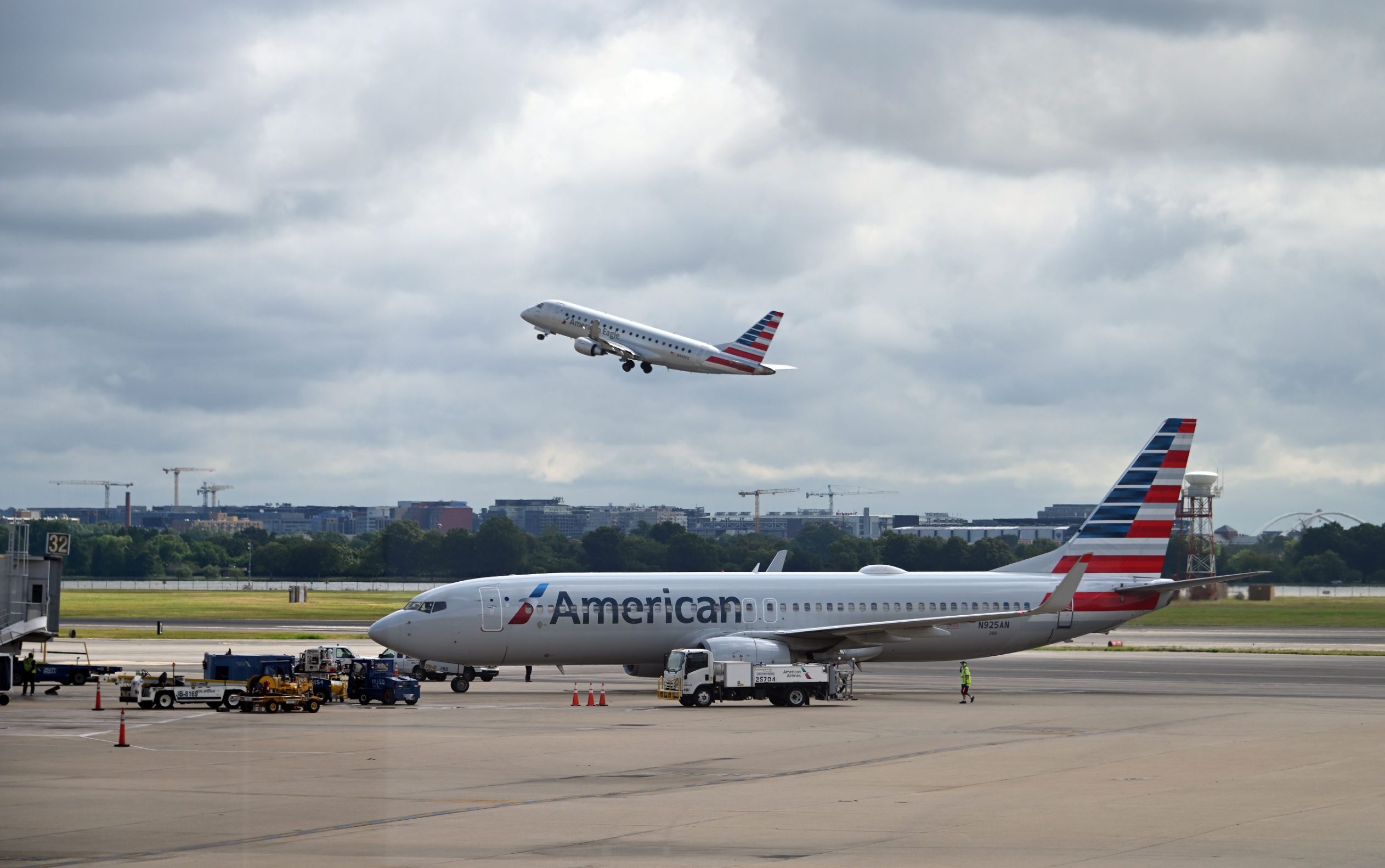 (FILES) In this file photo an American Eagle plane takes off while an American Airlines plane approaches a gate at Ronald Reagan Washington National Airport on July 10, 2020, in Arlington, Virginia, during the coronavirus pandemic. - American Airlines said on August 25, 2020 it will lay off 19,000 workers on October 1, in addition to thousands more who left the company or agreed to voluntary furloughs, unless Congress offers more aid. 